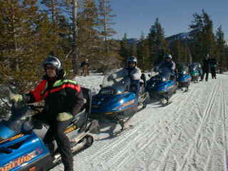 Here geared up and ready to go a group of vacation visitors from Accommodation Tahoe wait to begin their snowmobile adventure.  Snowmobililing is great fun.